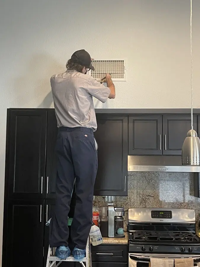 Technician inspecting an air vent during HVAC service in Lenexa